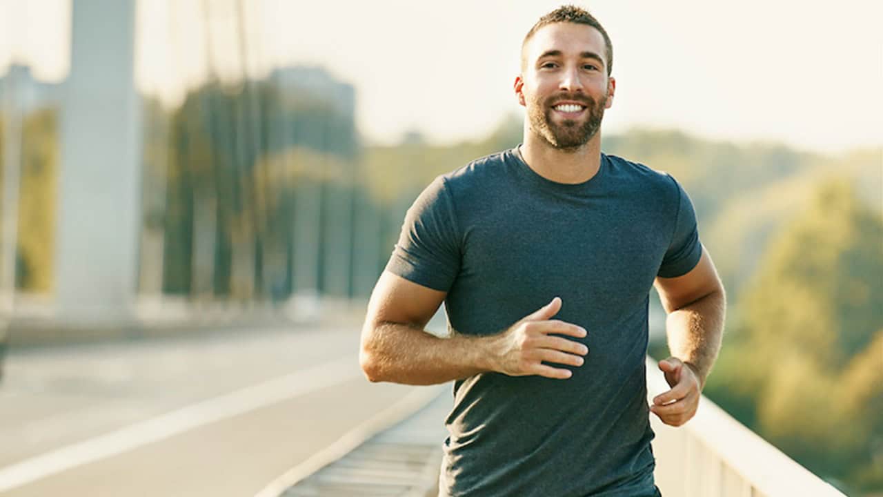 The Connection Between Lifestyle and Erectile Dysfunction Smiling man jogging outdoors on a sunny day, promoting fitness, wellness, and mental health.