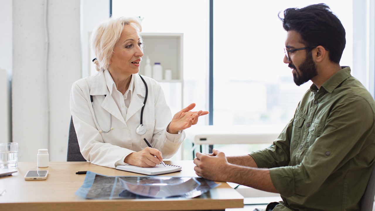Elder physician giving recommendations using notebook for writing prescription