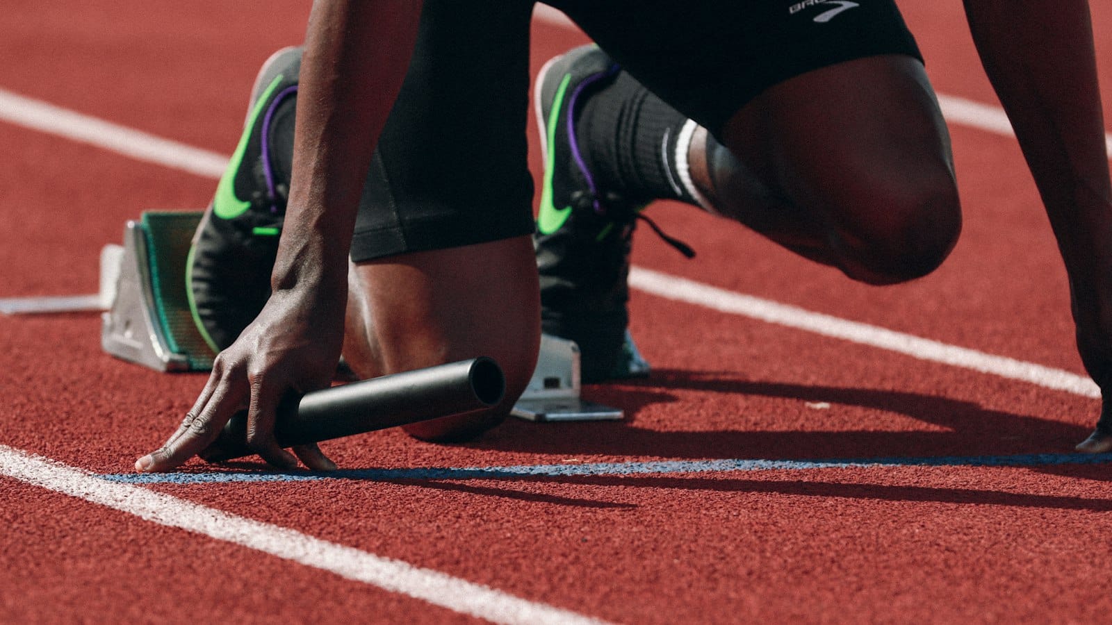 Sprinter crouched in the starting blocks on a red running track, a focused image for how to build self discipline by Josh Trent Wellness and Wisdom