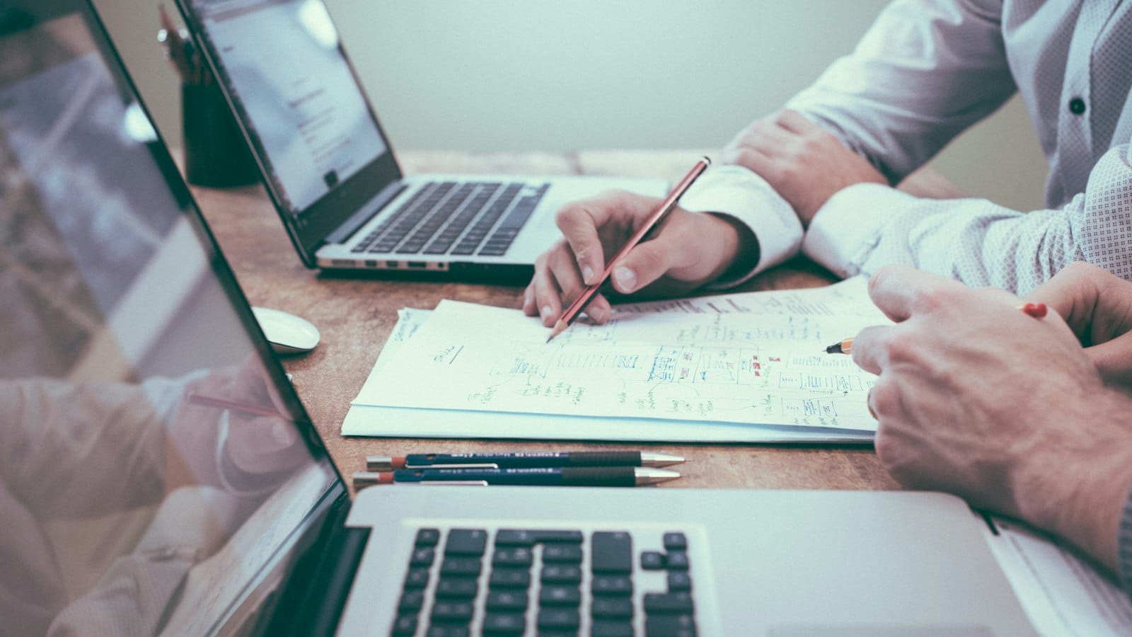 Two people reviewing handwritten notes beside laptops, an image of feedback for how to handle criticism by Josh Trent Wellness and Wisdom