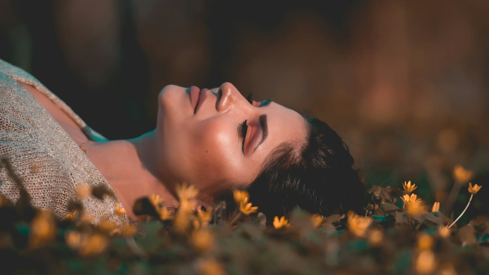 Woman resting peacefully among wildflowers with eyes closed, a calm offline image for how to reduce screen time by Josh Trent Wellness and Wisdom